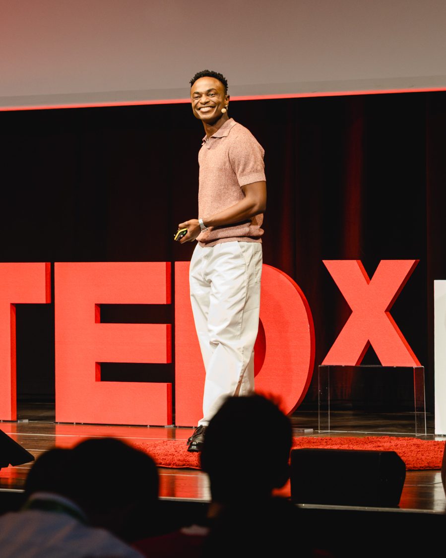 Adetayo smiling at the audience on the TEDx Linz stage